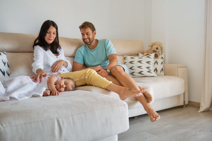 Pregnant mother and father looking at sleeping daughter in living room