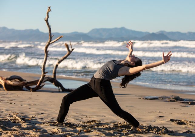 Young woman dancing and posing near water on shore