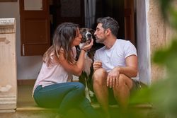 Happy couple kissing dog on porch