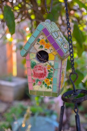 A colorful mosaic bird house in a garden