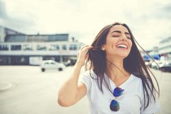 Woman touching her hair as it blows in the wind outside