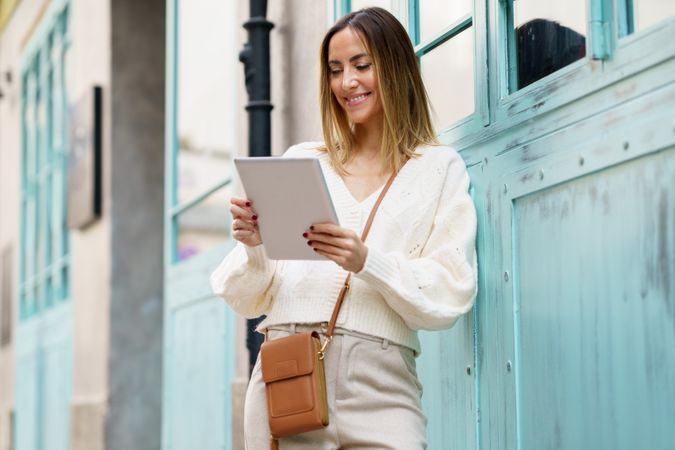 Woman in cream standing outside with digital tablet