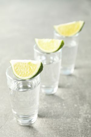 Tequila shots with lime slices on grey background