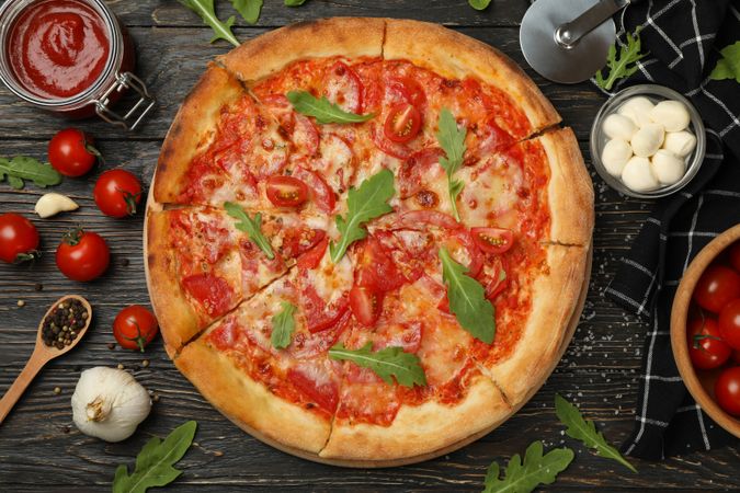 Tasty pizza and ingredients on wooden background