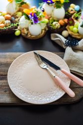 Easter holiday table setting with delicate pink plate surrounded by decorative eggs and colorful flowers