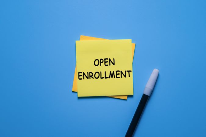open enrollment words on sticky notes with a black marker isolated on blue background