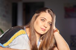Blonde woman with green sitting indoor looking away
