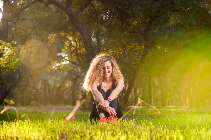 Happy woman sitting on sunny lawn