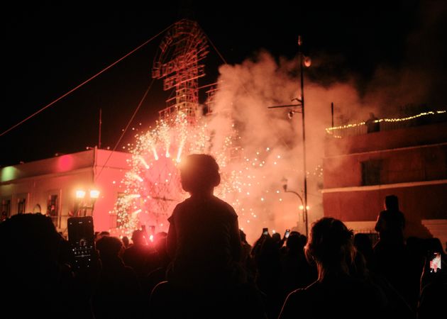 Silhouette of boy above crowd looking at fireworks ahead