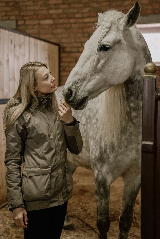 Woman hugging horse with long mane in face in stable