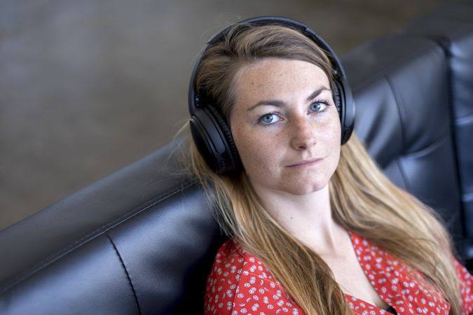 Woman at home sitting on leather couch wearing headphones