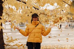 Smiling woman touching leaves on autumn tree