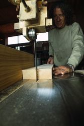 Mature male woodworker cutting plank with band saw