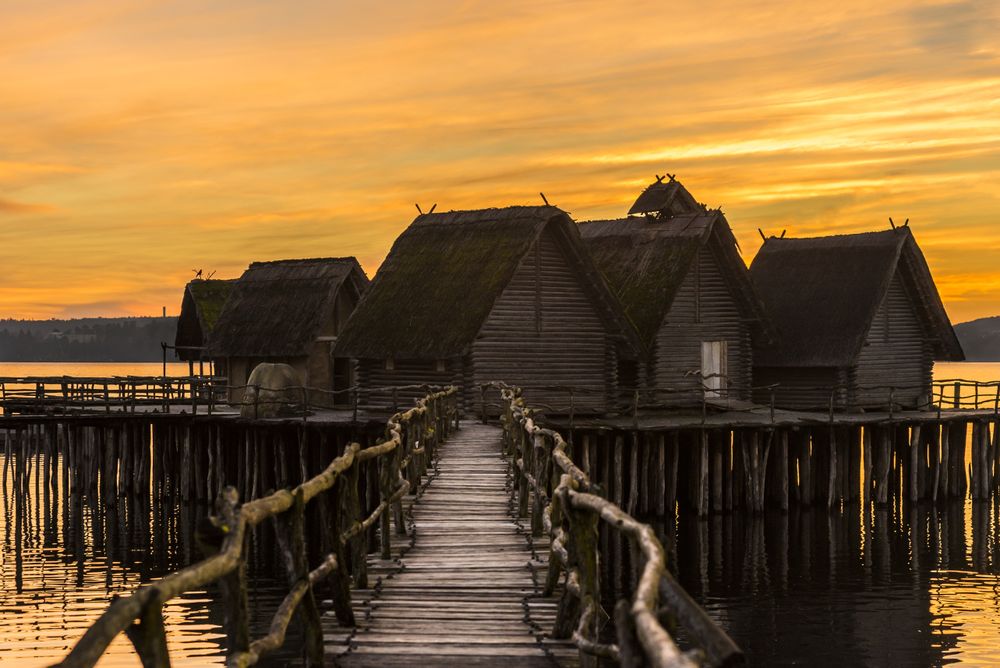 Wooden bridge and houses suspended over lake water