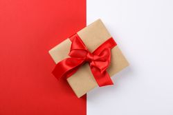 Beautiful gift box with red bow on two tone background, space for text