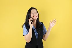 Young Asian Woman Making a Call Using a Cell Phone With Eye Closed, Happy Smiling Gesture.