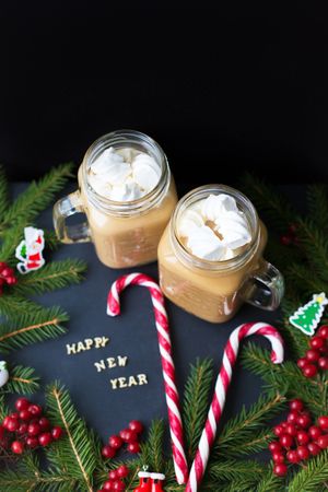 A cup of coffee with marshmallows, Christmas ornaments and candy.
