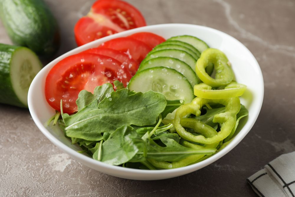 Plate with fresh vegetable slices on grey background, close up