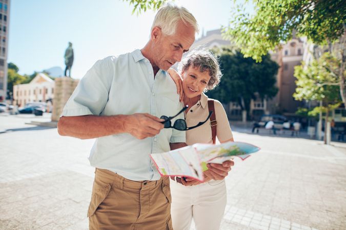 Mature couple standing outdoors in the city looking at a map