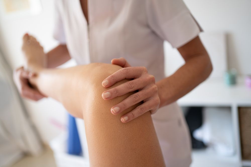 Professional physiotherapist treating knee of patient