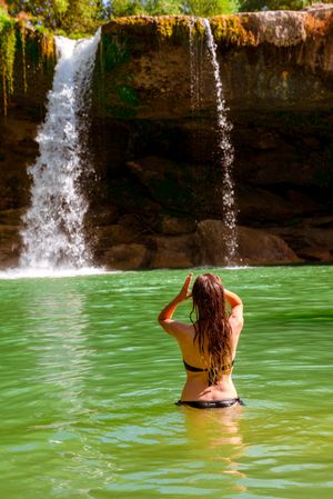 Anonymous female standing near amazing waterfall