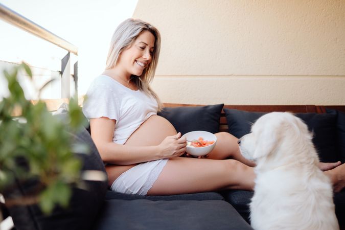 Smiling pregnant woman chilling with dog