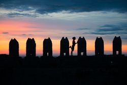 Silhouette of person between stone sculptures in sunset