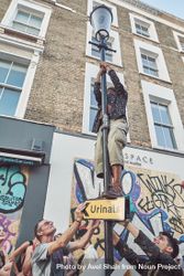 London, England, United Kingdom - August 25th, 2019: Man standing on streetlight in London 0V6y30