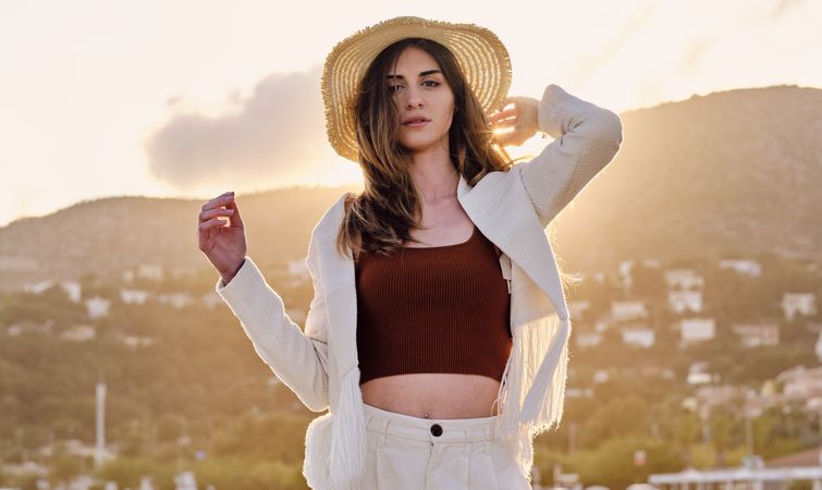 A long hair fashion model with a hat at the beach at sunset in a summer day