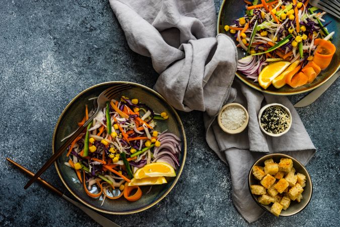 Top view of two fresh salad with finely chopped vegetables and lemon slices in bowl on counter with copy space