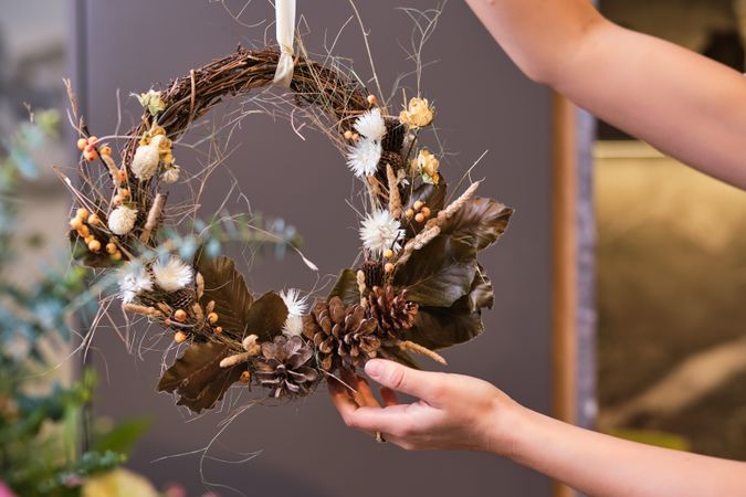 Faceless florist with withered handmade wreath in store