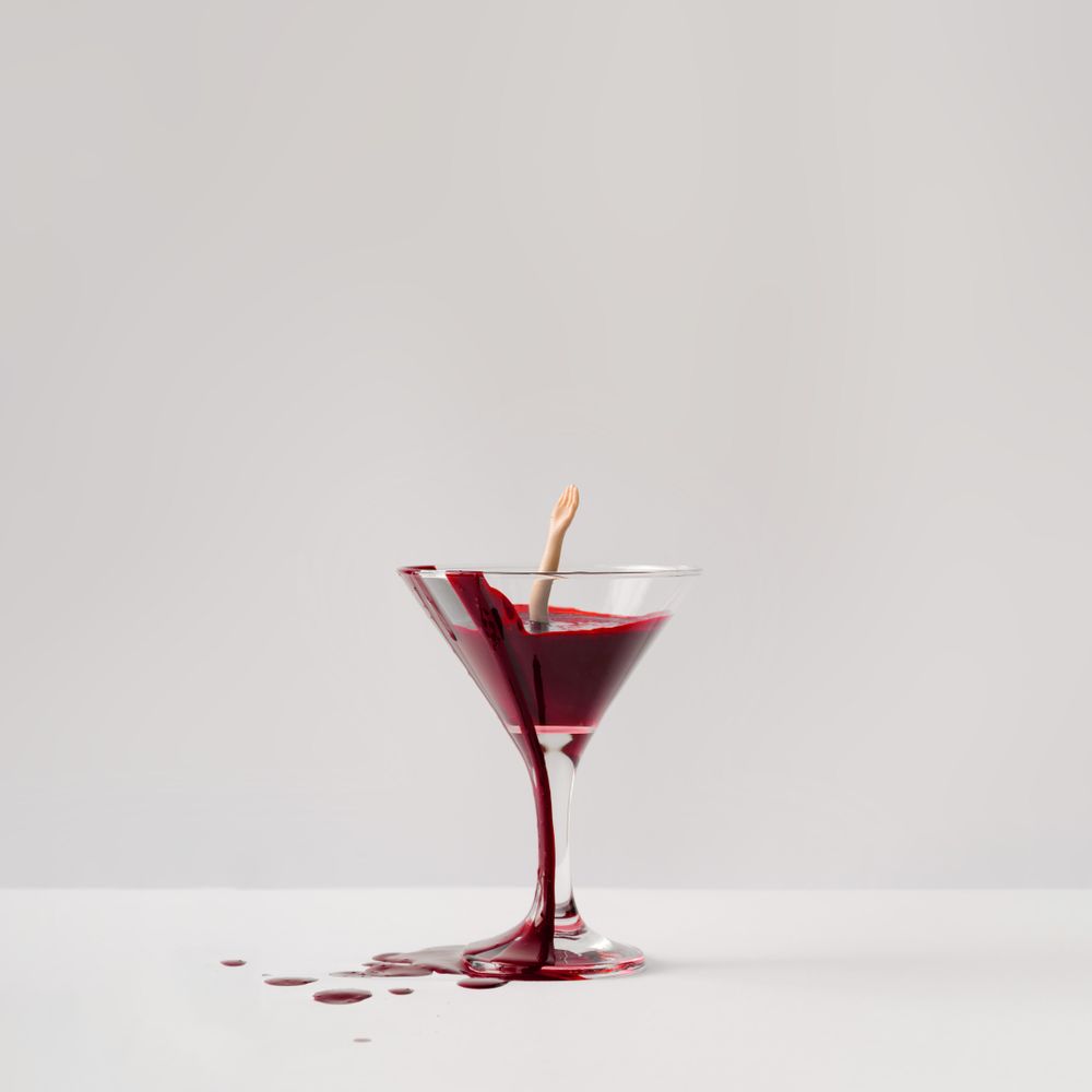 Doll hand drowning in martini glass full of blood