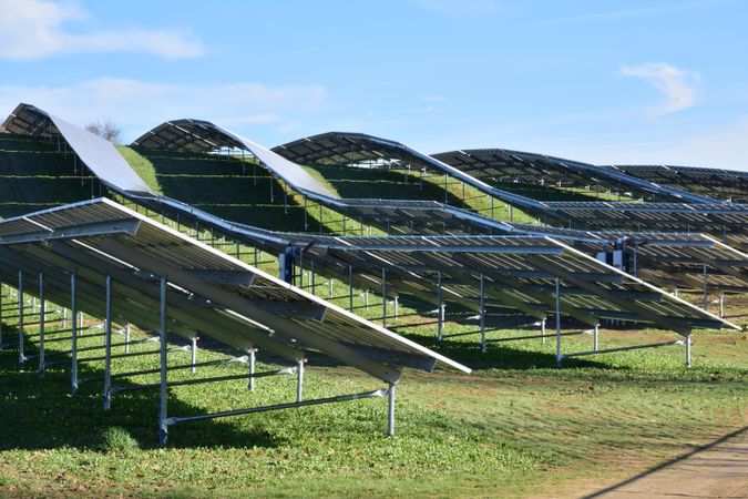 Solar panels on green grass field under blue sky