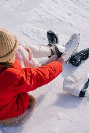 Woman sitting on snow and changing boots