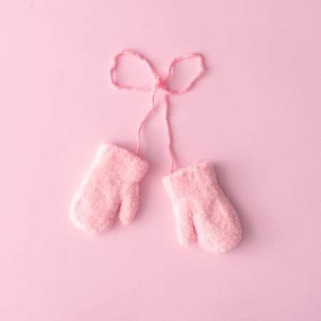 Pink wool gloves against pink background