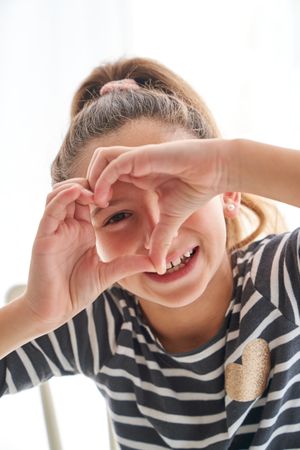 Funny girl making heart gesture
