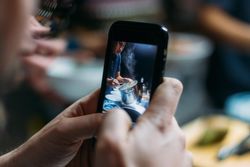 Person taking picture on phone of someone cooking pasta