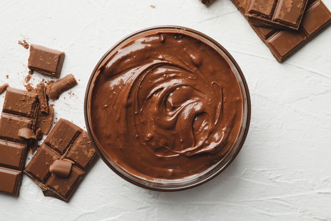 Bowl with chocolate and chocolate pieces on neutral background