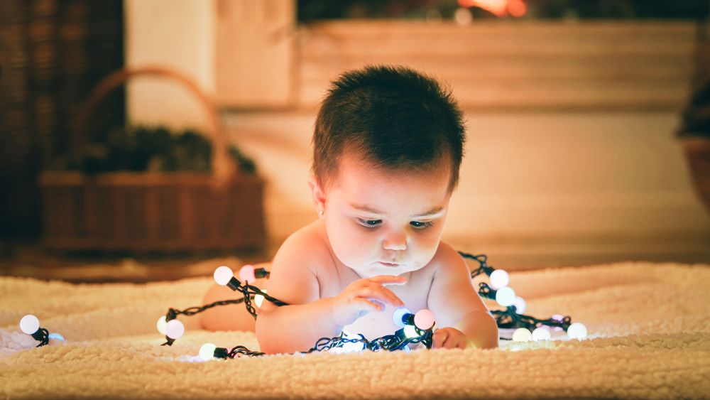 Baby playing with light garland on Christmas Day