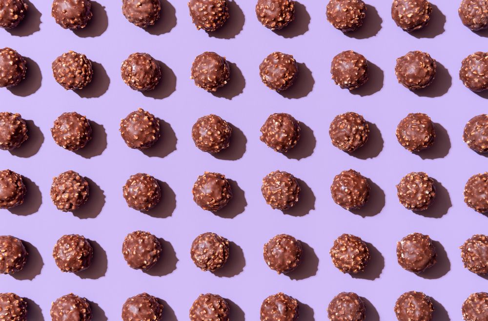 Chocolate candies aligned on a purple background