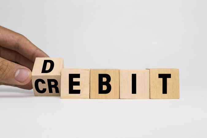 male hands flip wooden blocks with debit and credit words text