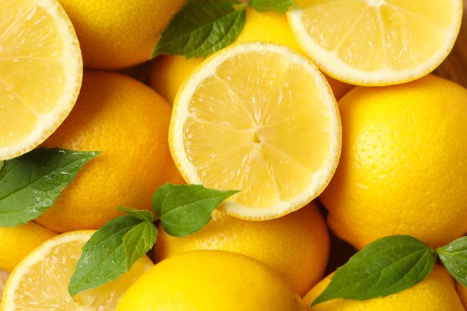 Lemons with leaves on whole background, close up. Ripe fruit