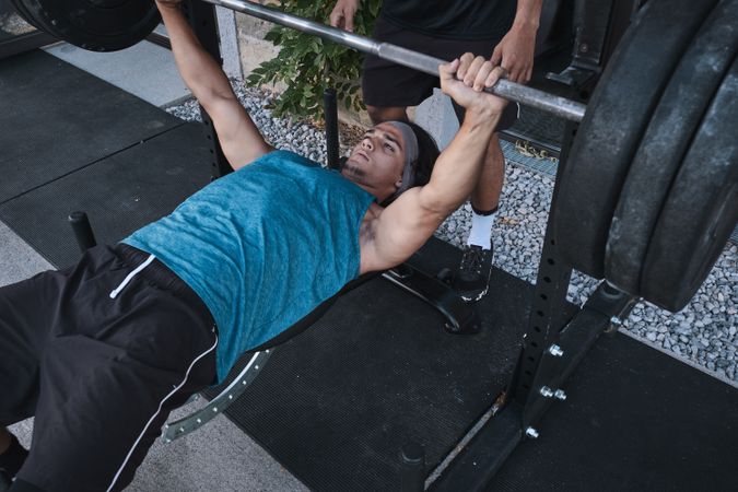 man lifting barbell with trainer