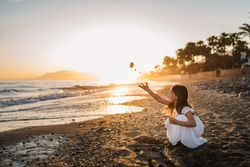 Adorable girl playing on seaside at sunset