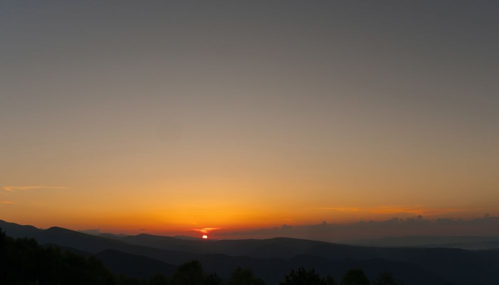 Golden sunset over mountains with clear sky.