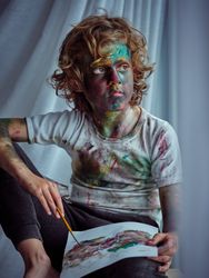 Boy with painted face looking away and drawing