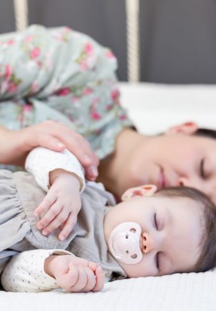Young mother and her baby girl sleeping in the bed