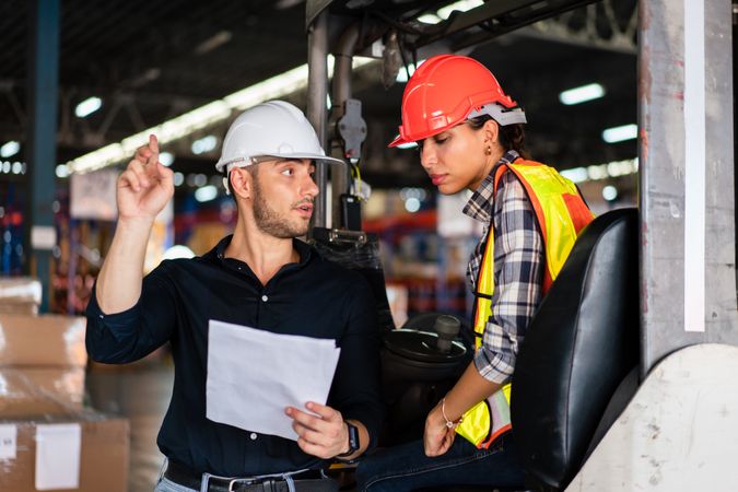 Warehouse supervisor and female forklift operator reviewing documents