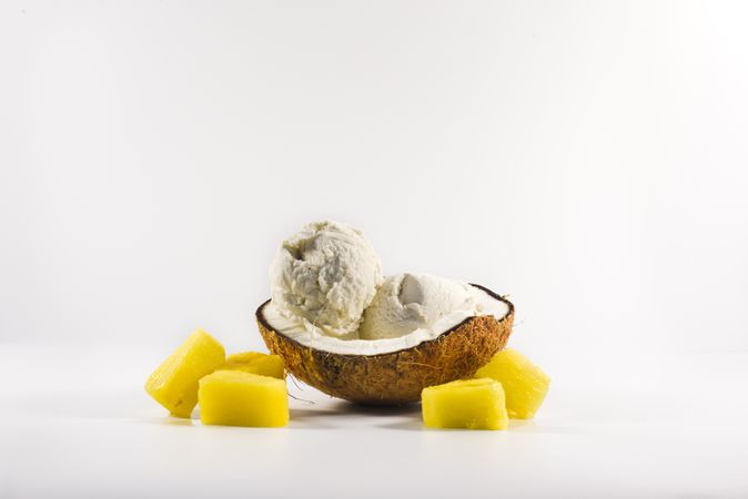 Coconut shell with scoop of pineapple ice cream and fruit chunks