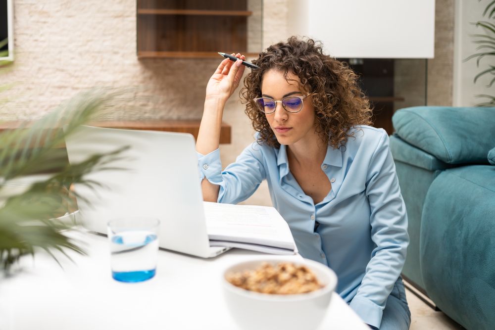 Woman taking notes from laptop at home
